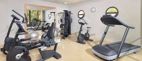 A fitness room with various exercise equipment including treadmills, elliptical machines, and weight machines.