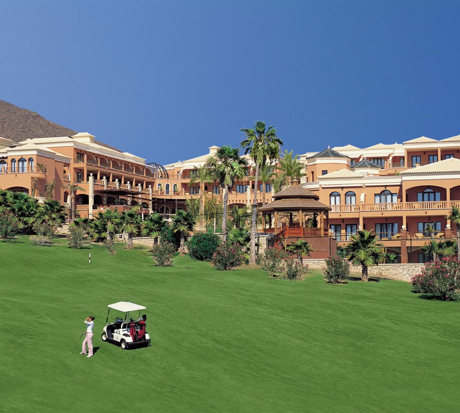 Un campo de golf con un club de campo y un edificio con varios balcones y un pabellón.