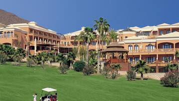 Un campo de golf con un club de campo y un edificio con varios balcones y un pabellón.