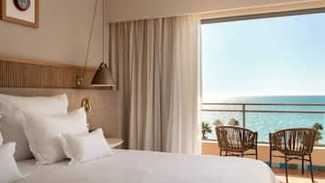 A hotel room with a bed, a nightstand, a lamp, a framed picture, and a view of the ocean.
