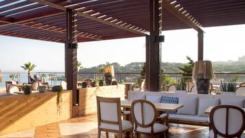 An outdoor patio with wooden furniture, a wooden counter, and potted plants.