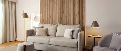 Una sala moderna con un sofá, un reposapiés, dos lámparas de pie y una pared de acento de madera.