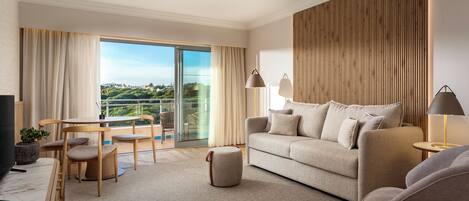 A modern living room with a sofa, armchairs, a TV, and a balcony with a view.