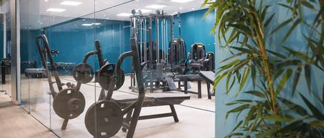 Een moderne sportschool met trainingsapparatuur, glazen wanden en een blauwe muur.