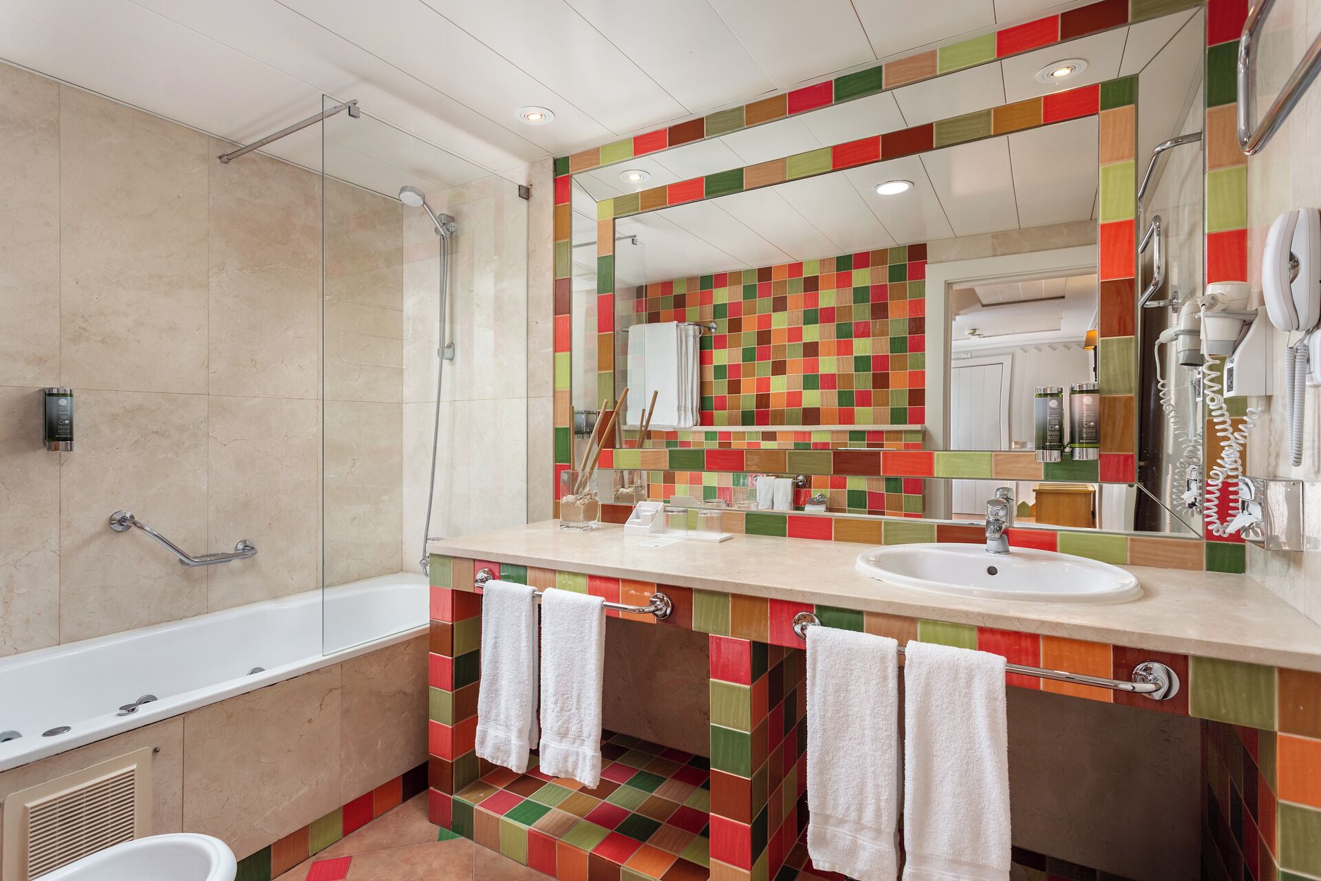 A modern bathroom with a large bathtub, a shower, and a vanity with a colorful tile backsplash.