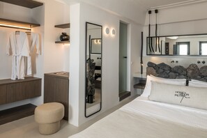 A modern bedroom with a bed, a mirror, a robe rack, and a small stool.