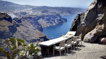 A table set on a rocky terrain overlooking a coastal landscape with a view of the sea and cliffs.