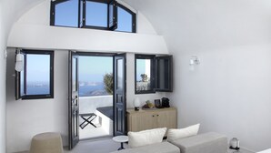 Een moderne kamer met een bank, een tafeltje, een kast en uitzicht door open deuren.