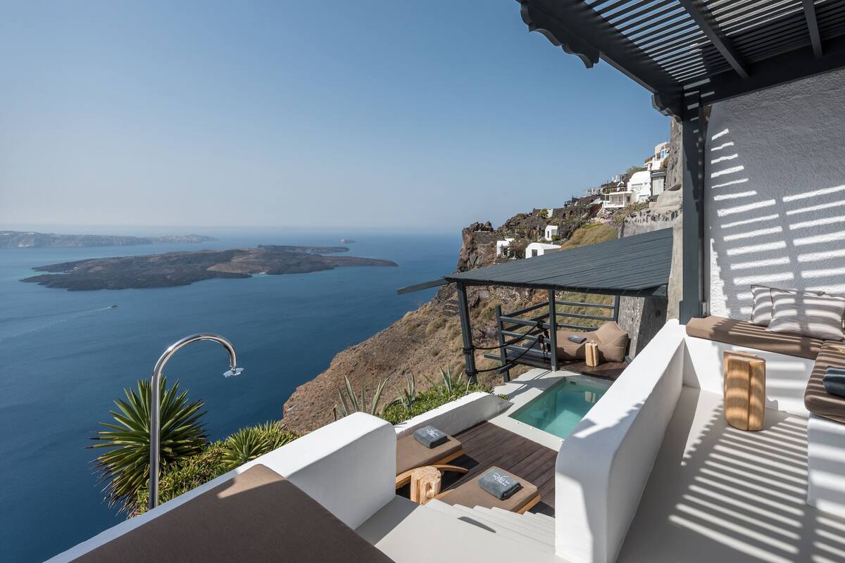 Ein luxuriöser Außenbereich mit Pool, Liegestühlen und Blick auf das Meer und die Inseln.