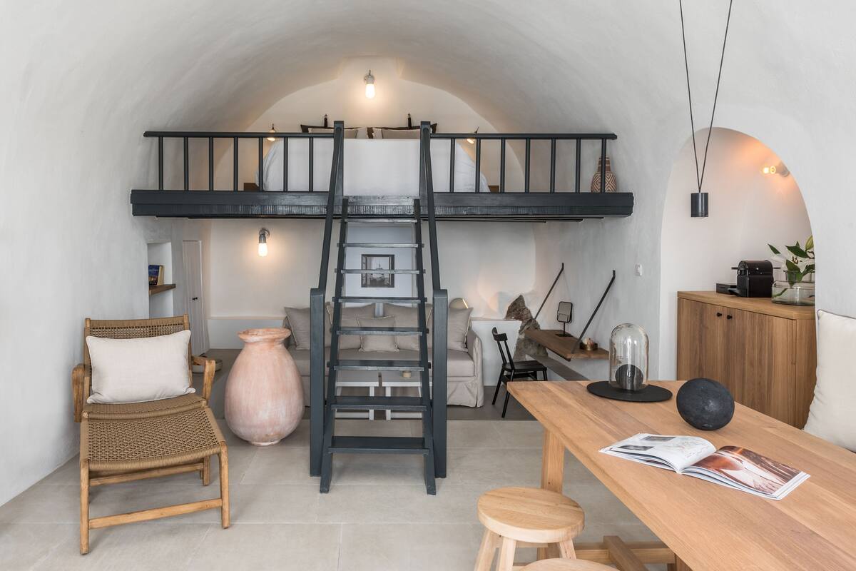 Ein Schlafzimmer im Loft-Stil mit Etagenbett, einer Halterung, einem Korbstuhl, einem Holztisch und einer großen Vase.