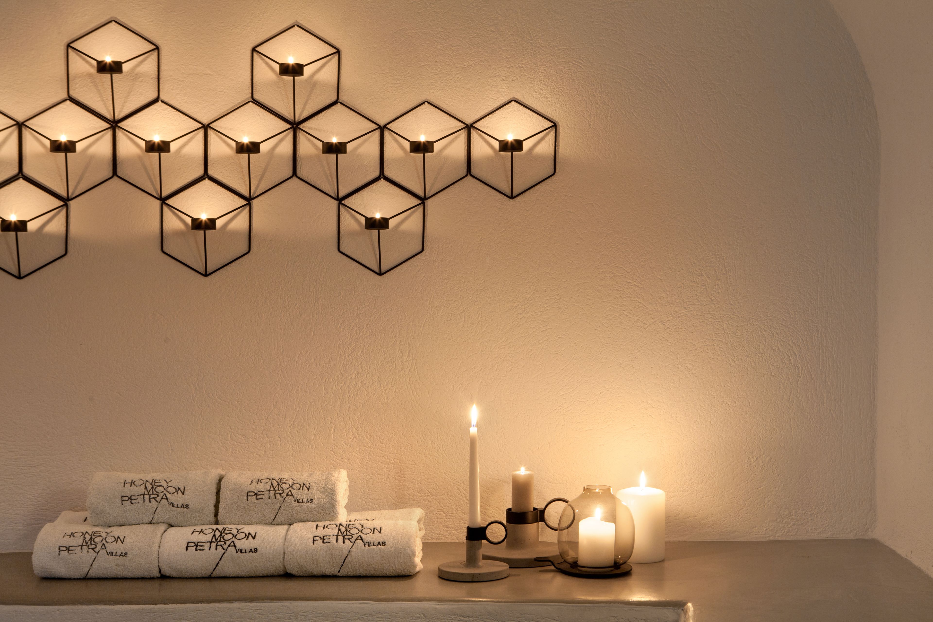 A wall-mounted hexagonal light fixture with candles and towels on a table.