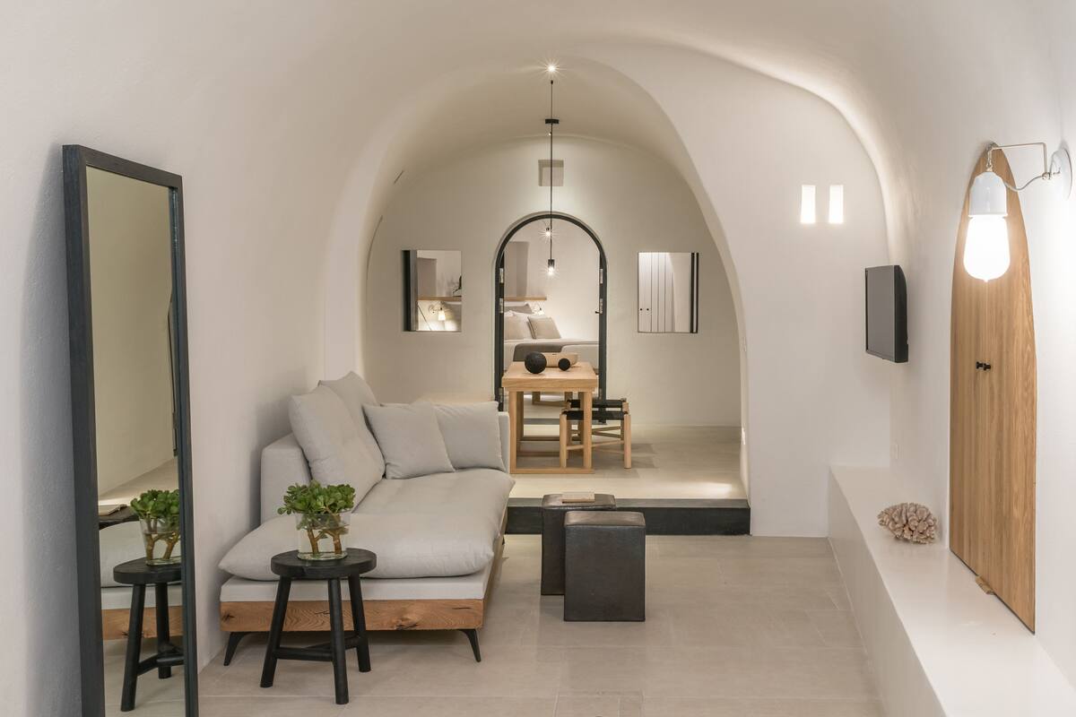 Ein modernes Interieur mit einer Couch, einem kleinen Tisch mit Pflanzen, einem Spiegel und einer Holztür.