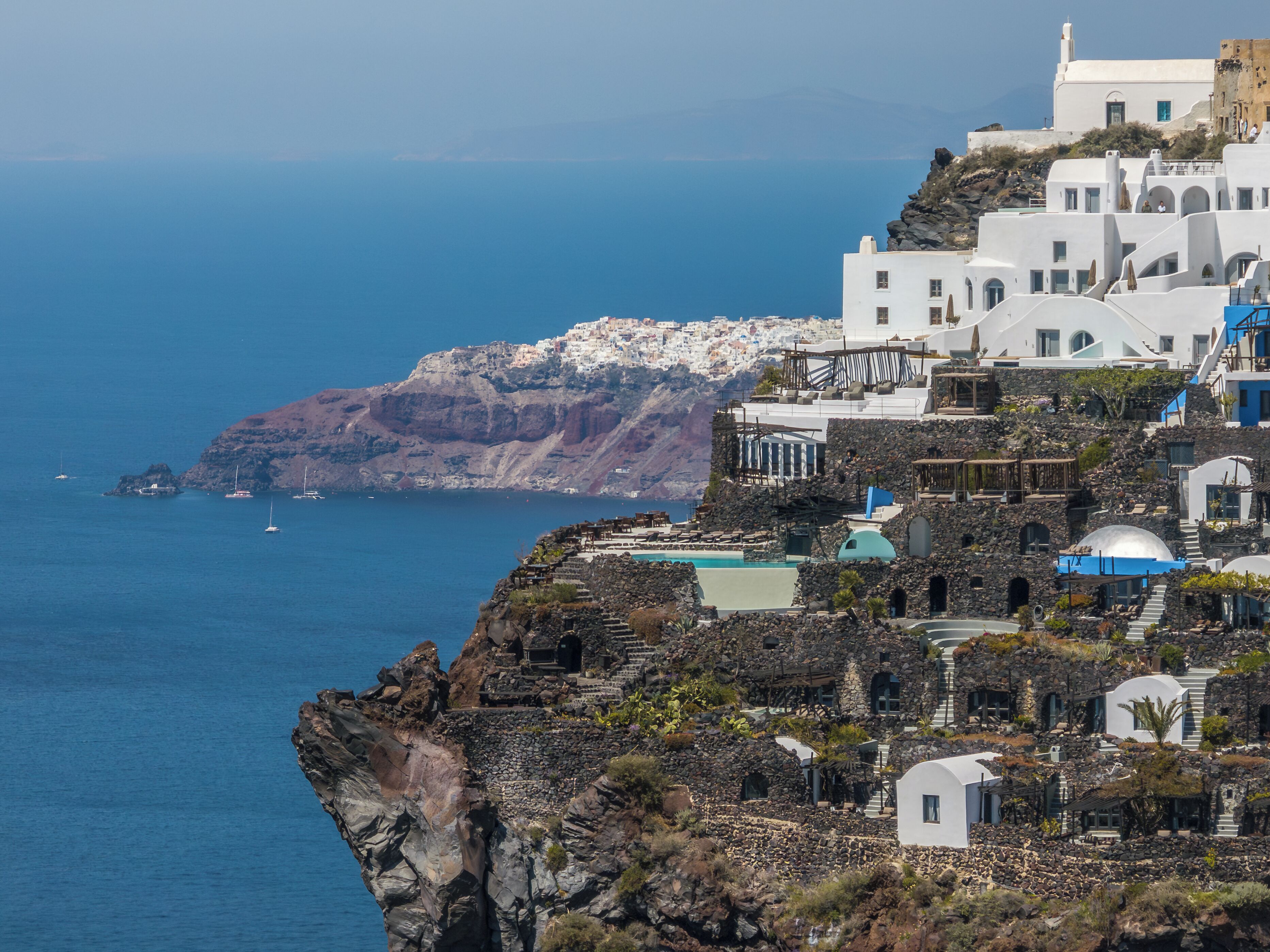 Un pueblo costero con edificios blancos, un acantilado rocoso y el mar.