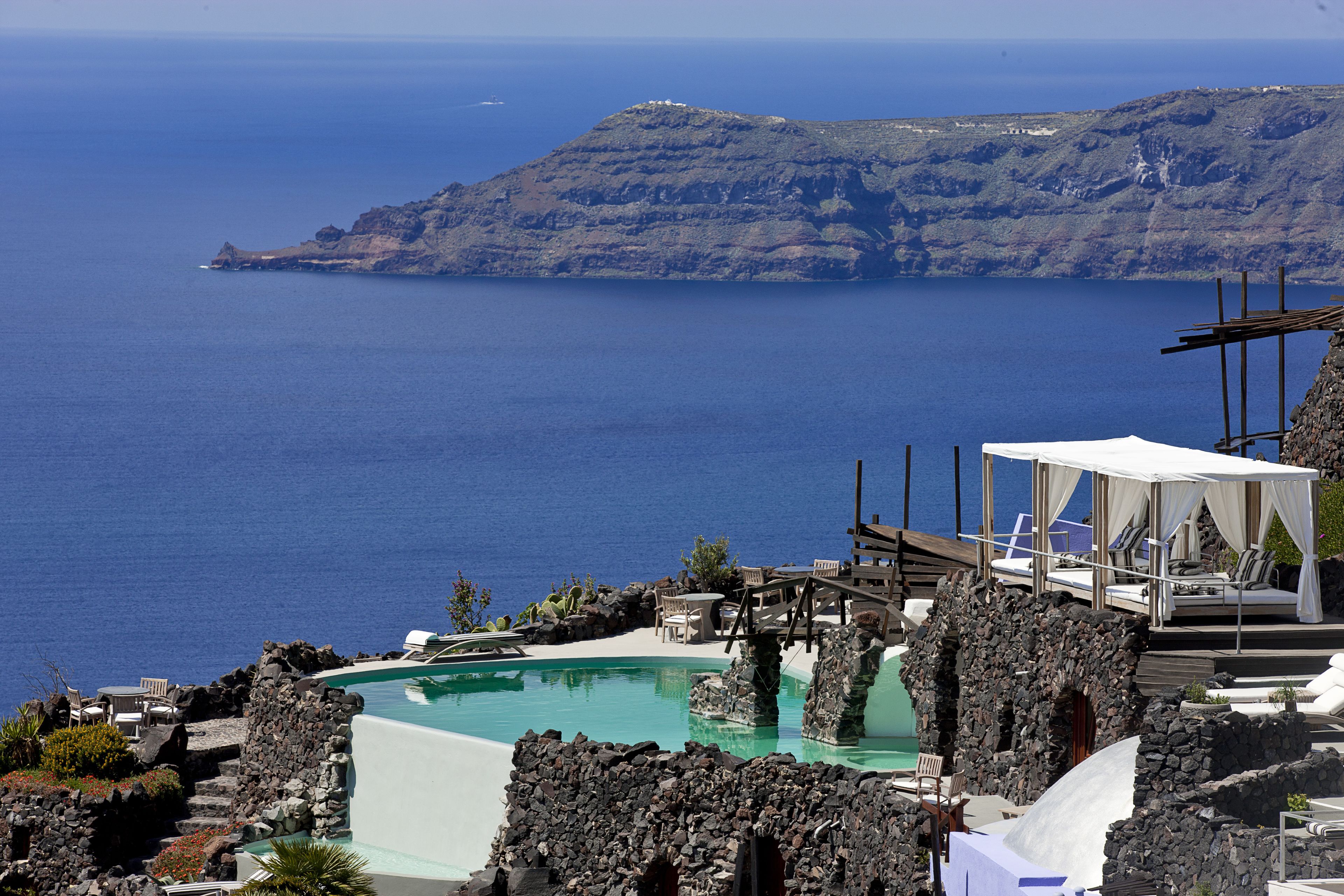 A resort with a pool, lounge chairs, and a view of the sea.