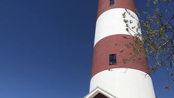 Un phare doté d’une tour à rayures rouges et blanches, une pancarte indiquant « PHARE D’ASSATEAGUE », et une petite entrée avec une porte.