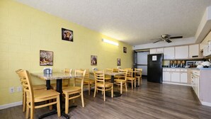 A dining area with wooden chairs and a marble table, a kitchen with white cabinets, and a ceiling fan. - 1st Choice Inn Rawlins (Rawlins)
