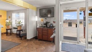 A hotel lobby with a reception desk, a television mounted on the wall, and a view of the outside through the glass doors. - 1st Choice Inn Rawlins (Rawlins)