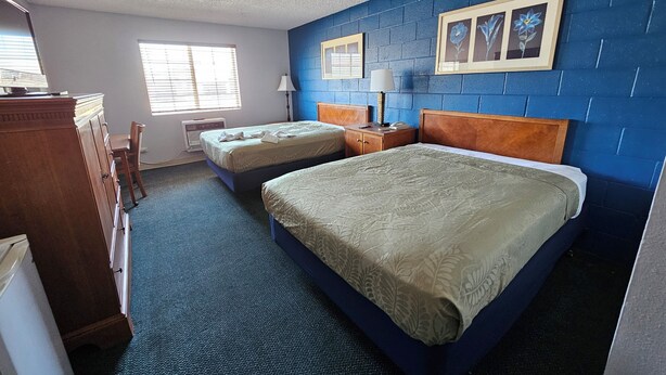 A hotel room with two beds, a dresser, a desk, and a window with blinds. - 1st Choice Inn Rawlins (Rawlins)