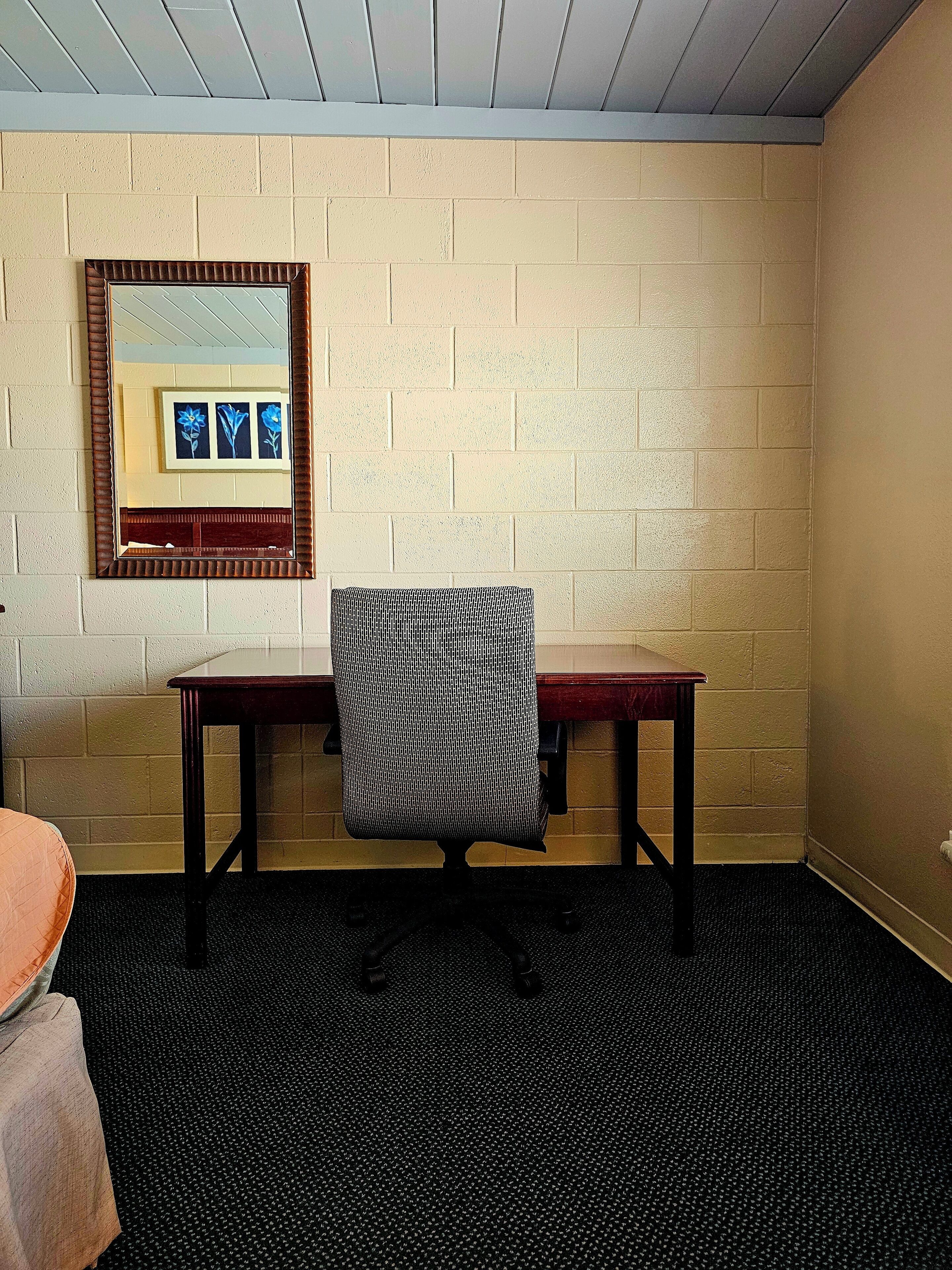 Een kamer met een bakstenen muur, een houten tafel, een stoel en een zwart tapijt.