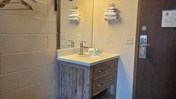A bathroom with a wooden vanity, a mirror, a sink, and a towel rack.