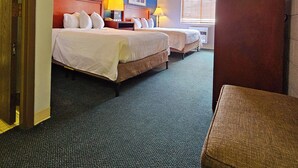 A hotel room with two beds, a wooden wardrobe, a desk, and a window with blinds. - 1st Choice Inn Rawlins (Rawlins)