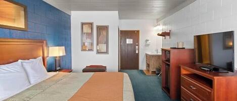 A hotel room with a bed, a TV, a desk, and a bathroom.