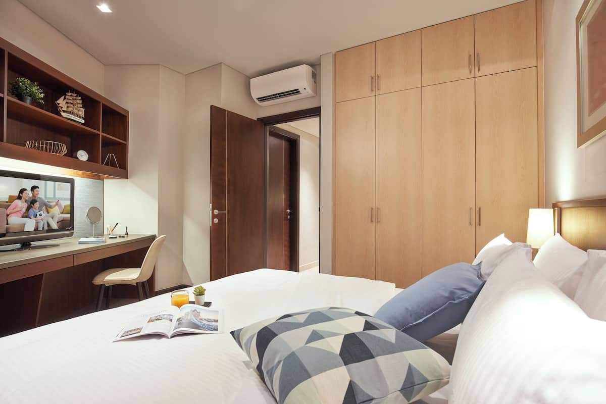 A hotel room with a bed, a desk with a computer, a television, and a wardrobe.