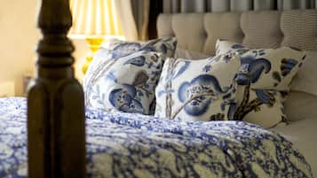 A neatly made bed with blue and white patterned bedding, a wooden headboard, and a lamp on a bedside table.