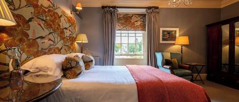 Hotelkamer met een groot bed, een zithoek met een stoel, een tafel met een lamp en een raam met gordijnen.