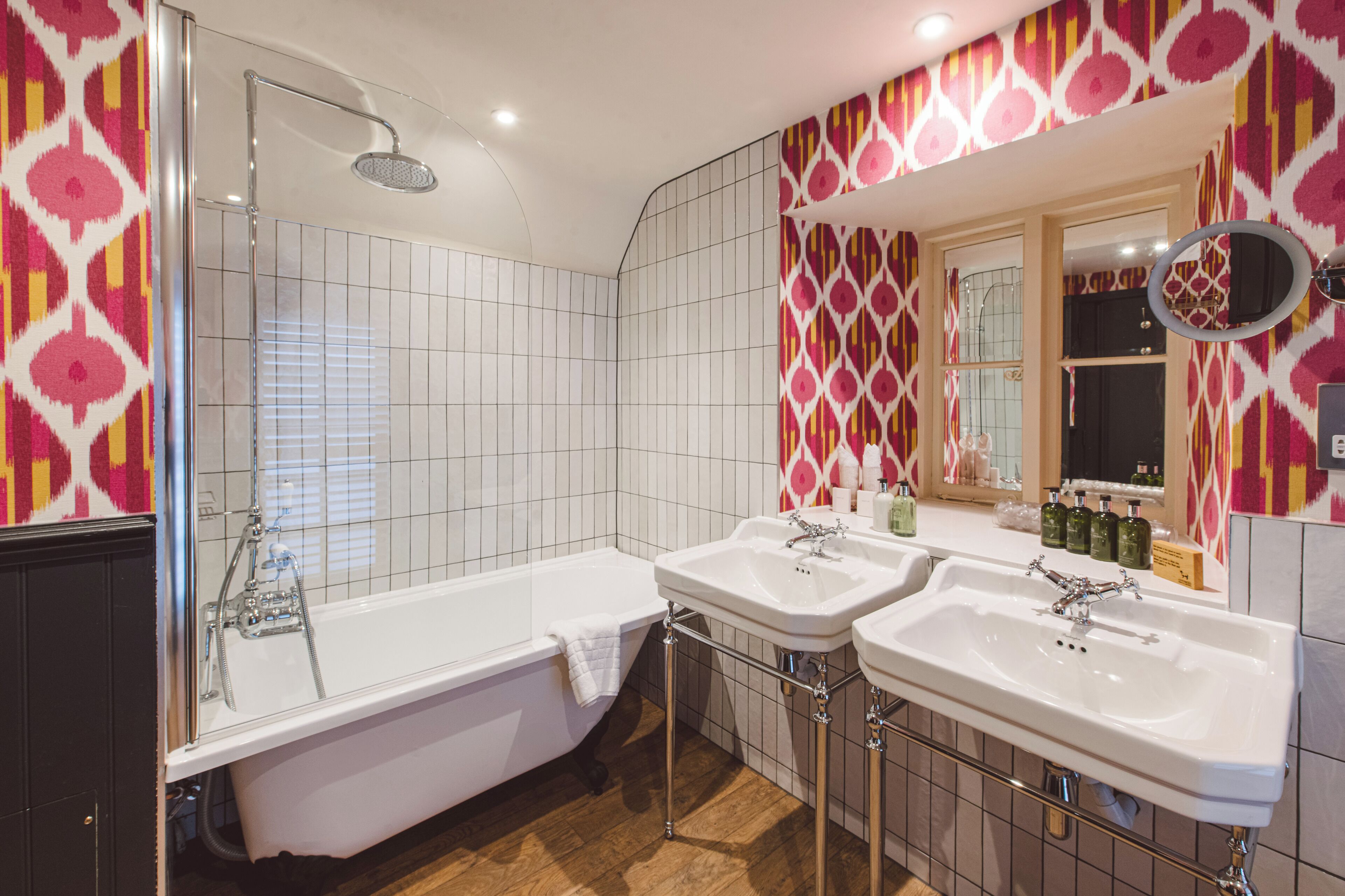 A modern bathroom with a freestanding bathtub, two sinks, and a shower.