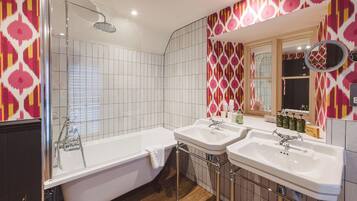 A modern bathroom with a freestanding bathtub, two sinks, and a shower.