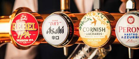 Un barman sostiene una llave de cerveza con diferentes etiquetas.