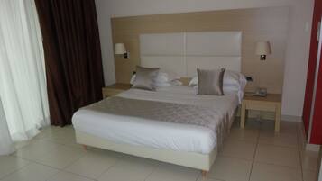A hotel room with a large bed, two bedside tables, and a headboard.