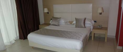 Une chambre d’hôtel avec un grand lit, deux tables de chevet et une tête de lit.