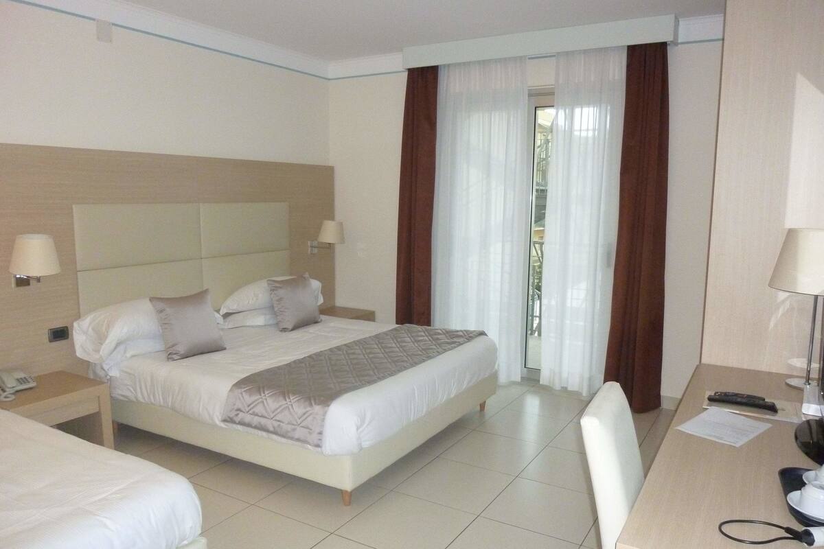 Una habitación de hotel con una cama, mesitas de noche, un escritorio y una silla.