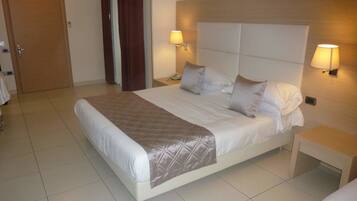 A neatly made bed with a quilted blanket, two bedside lamps, and a wooden headboard.