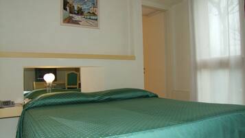 Una habitación de hotel con una cama, una mesita de noche, un espejo y un cuadro en la pared.