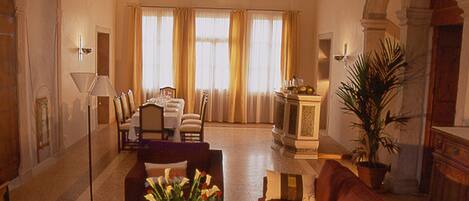A spacious living room with a red sofa, a coffee table with a book, and a dining area with a chandelier.