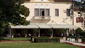 A building with a balcony, outdoor seating, and a garden. - Villa Ca' Sette (Bassano del Grappa)