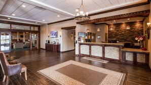 A spacious lobby with a reception desk, a large chandelier, and a stone wall. - Best Western Plus Flathead Lake Inn And Suites (Kalispell)