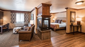 A hotel room with a fireplace, a bed, a desk, and a seating area. - Best Western Plus Flathead Lake Inn And Suites (Kalispell)