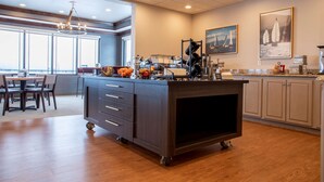 A modern kitchen with a central island, a dining area with a view, and artwork on the walls. - Best Western Plus Flathead Lake Inn And Suites (Kalispell)