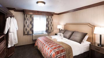 A hotel room with a bed, a bedside table with a lamp, a wardrobe, and a window with curtains.