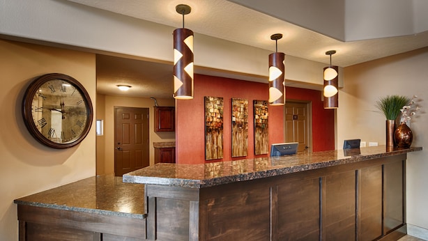 A reception area with a marble counter, a wall clock, and three pendant lights. - Best Western Mesquite Inn (Mesquite)