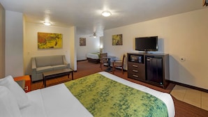 A hotel room with a bed, a sofa, a desk, a television, and artwork on the walls. - Best Western Mesquite Inn (Mesquite)