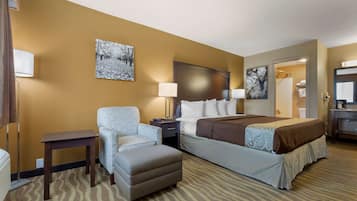 A hotel room with a bed, a chair, a small table, and a nightstand.