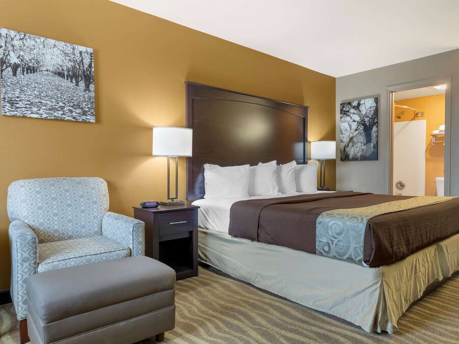 Een hotelkamer met een groot bed, een stoel, een nachtkastje en een bureau.