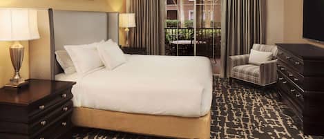 A hotel room with a large bed, a dresser, a chair, and a television.