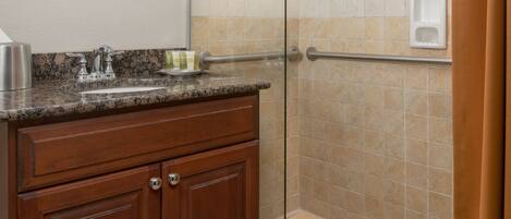 Un bagno con box doccia in vetro, mobile lavabo in legno e specchio.