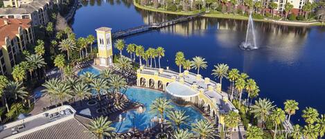 A resort with a central pool, palm trees, and a water fountain.